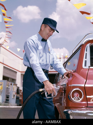Negli anni sessanta la stazione di servizio operatore con il tubo della pompa di riempimento del serbatoio del gas di automobile Foto Stock