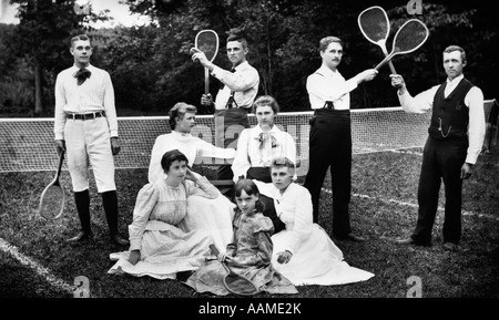 1890s del volgere del secolo ritratto di gruppo di uomini che tengono le racchette & LE DONNE E UN BAMBINO DI FRONTE AL NETTO SUL CAMPO DA TENNIS D'ERBA Foto Stock