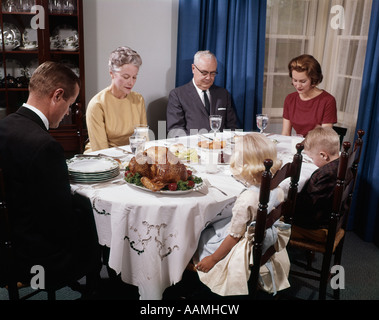 Anni sessanta tre generazioni la famiglia insieme intorno vacanza Tavola di Cena dicendo grazia preghiera uomo donna ragazzo ragazza Foto Stock