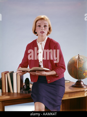 Anni sessanta DONNA CON APRI LIBRO seduti sulla scrivania tra libri e globo scuola insegnante di professione LAVORO DEGLI ALTOPARLANTI Foto Stock