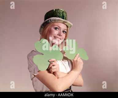 Anni sessanta anni settanta irlandese retrò donna sorridente AZIENDA GREEN trifogli e indossando Partito Verde HAT Foto Stock
