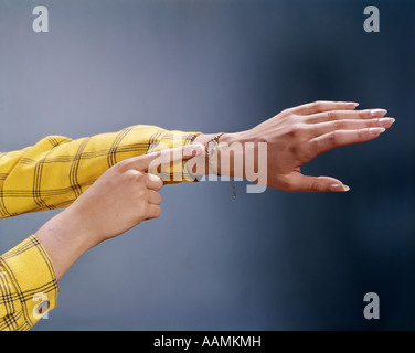 1970 anni settanta donna mani il dito puntato all'OROLOGIO DA POLSO giallo e nero controllato manicotti tempo Orologi gioielli retrò Foto Stock