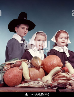 Anni Cinquanta 3 Bambini 2 ragazze 1 ragazzo vestito IN PURITAN PELLEGRINI COSTUMI RACCOLTO DI ZUCCA VERDURE IN PRIMO PIANO Foto Stock