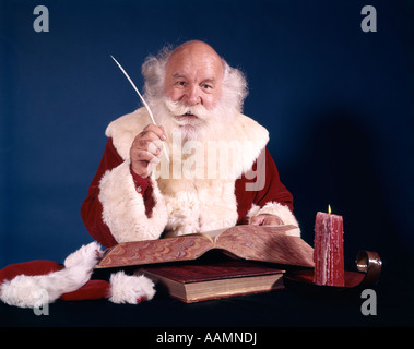 Anni sessanta SANTA seduto alla scrivania con il libro aperto facendo una lista con la penna del cappello Foto Stock