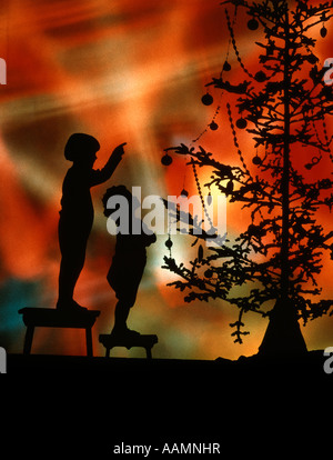 SILHOUETTE di 2 bambini su sgabelli guardare al puntando al albero di Natale colorato sfondo luci retro vintage Foto Stock