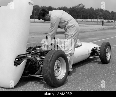 Anni sessanta anni settanta uomo DRIVER MECCANICO DI INTERVENIRE SUL MOTORE DI AUTO DA CORSA IN BUCA su asfalto LOTUS FORD Foto Stock