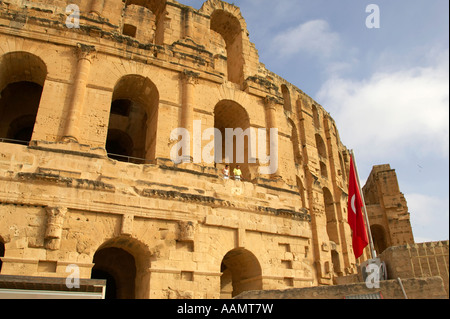 Bandiera tunisina e turisti nel vecchio Colosseo romano contro blu cielo nuvoloso el jem tunisia Foto Stock