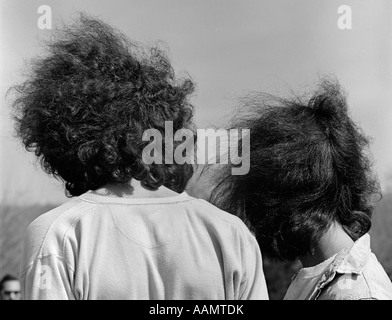 Anni sessanta anni settanta C perdono di vista posteriore del HIPPIE BOY & ragazza giovane uomo e donna con lunghi capelli selvaggi soffiaggio libero nel vento Foto Stock