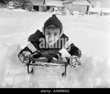 Anni Cinquanta BOY sulla slitta in Snow guardando la fotocamera Foto Stock