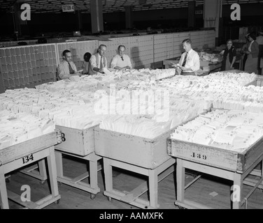 Anni Cinquanta uomini 4 sorta di smistamento della posta lettere da grandi scomparti pieno farcito con molte buste Foto Stock