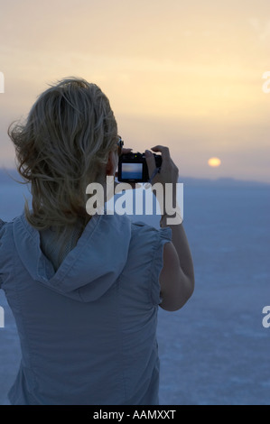 Verticale dai capelli biondi turista femminile scatta una fotografia del sorgere del sole sopra le saline chott el djerid tunisia Foto Stock