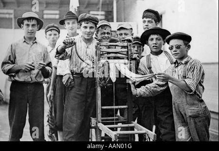 1930 un gruppo di ragazzi della città mette in moto la biancheria bagnata attraverso meccanica strizzatoio vestiti guardando la fotocamera Foto Stock