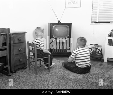 Degli anni Cinquanta vista posteriore di 2 ragazzi IN STRIPED T-shirt di guardare la TV Foto Stock