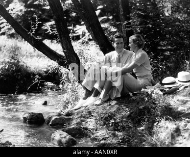 1930s giovane uomo donna seduta accanto a lato del flusso A FIANCO DI PARLARE FLIRTARE DATA DATING Foto Stock