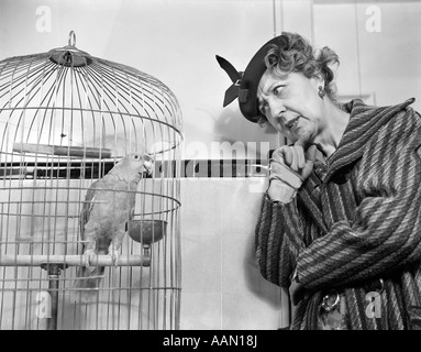 1940s divertente DONNA IN HAT & rivestire parlando a pappagallo in gabbia per uccelli Foto Stock