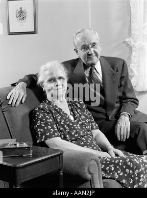 Negli anni quaranta anni cinquanta coppia di anziani seduti sul divano a sorridere guardando la fotocamera Foto Stock