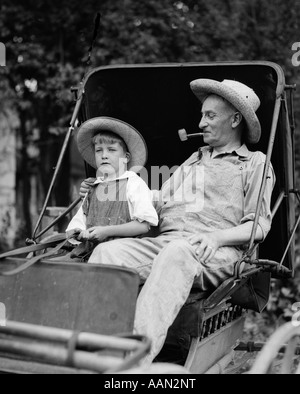 1930s FARM BOY & nonno in tute e cappelli di paglia in seduta piccolo buggy Foto Stock