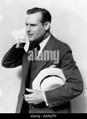 1930 L'UOMO IN TUTA HOLDING HAT TERGI faccia con fazzoletto Foto Stock