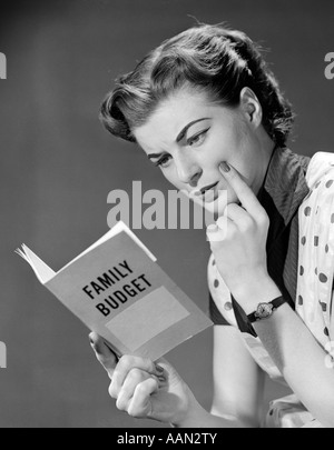 Anni Cinquanta la donna nel grembiule dito sulla guancia GUARDANDO AL BILANCIO FAMILIARE PRENOTA Foto Stock