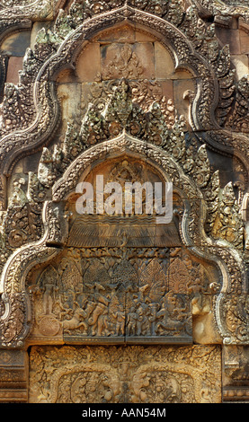 Intricate sculture di pietra arenaria 'incendio nella foresta Khandava', frontone orientale del nord biblioteca, Banteay Srei Temple, Cambogia Foto Stock