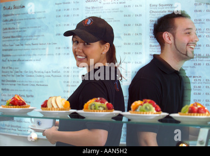 Cameriere e cameriera lavora in una moderna caffetteria con menu in background Foto Stock