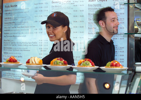 Cameriere e cameriera lavora in una moderna caffetteria con menu in background Foto Stock