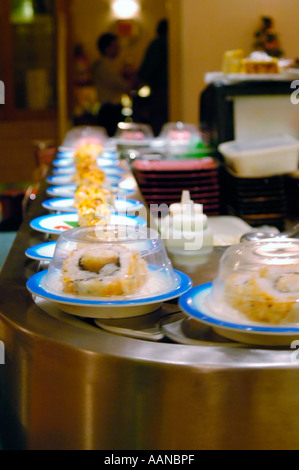 Il cibo giapponese piatti rotanti su un Sushi Bar ristorante nastro trasportatore Foto Stock