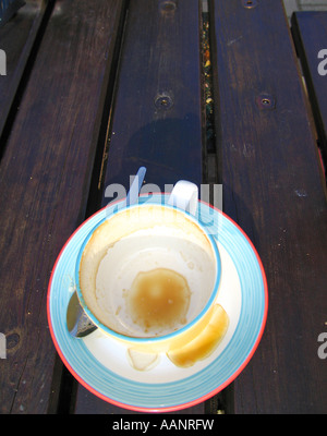 Svuotare una tazzina di caffè al di fuori sulla panca in legno tabella Foto Stock