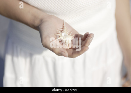Una giovane donna in possesso di una shell Foto Stock