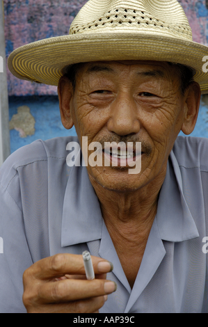 Ritratto di un vecchio uomo che indossa un cappello e fumare una sigaretta in Datong, Shanxi, Cina. Foto Stock
