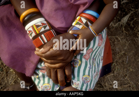 Close up di mani di donna Masai e il suo bambino indossando i braccialetti di tallone Riserva Nazionale di Masai Mara Kenya Africa orientale Foto Stock