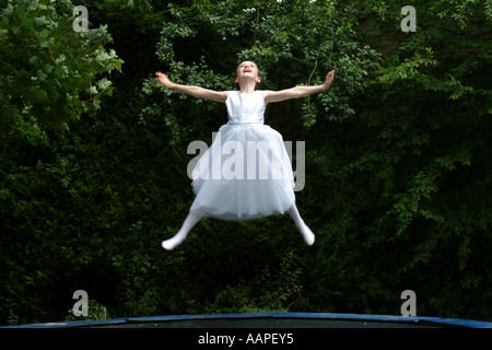 La ragazza di prima comunione vestito di saltare sul trampolino Foto Stock