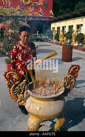 Donna immissione bruciare bastoncini di incenso in pentola, Diecimila Buddha Monastero, Sha Tin, Nuovi Territori di Hong Kong, Cina Foto Stock