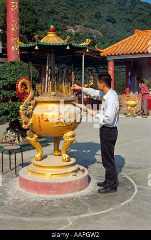 L'uomo immissione bruciare bastoncini di incenso in pentola, Diecimila Buddha Monastero, Sha Tin, Nuovi Territori di Hong Kong, Cina Foto Stock