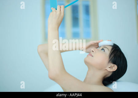 Una giovane donna azienda specchio con puff Foto Stock