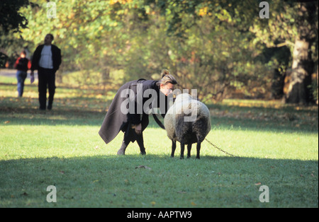 La donna parla di una pecora Mezotne nel parco del castello della Lettonia Foto Stock
