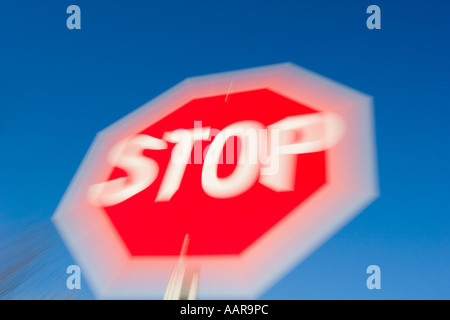 Segno di stop in rosso e bianco sole contro il cielo blu Foto Stock