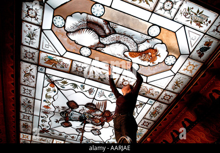 Una donna restauratore lavorando sulla conservazione del dipinto a mano in stile orientale di vetro il Royal Pavilion Brighton Foto Stock