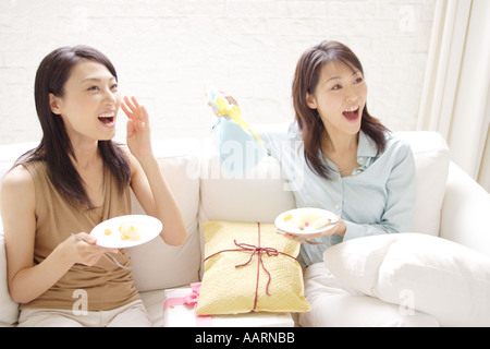 Due giovani donne godendo parte a casa Foto Stock