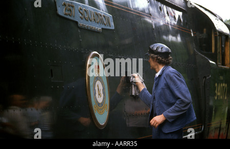 Uomo in tuta sul lato della grande battaglia della Gran Bretagna classe locomotiva a vapore in corrispondenza di una stazione di conservazione del sito del club Foto Stock