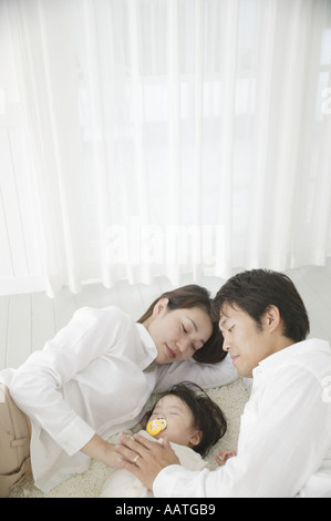Bambina che dorme con i genitori a guardare Foto Stock