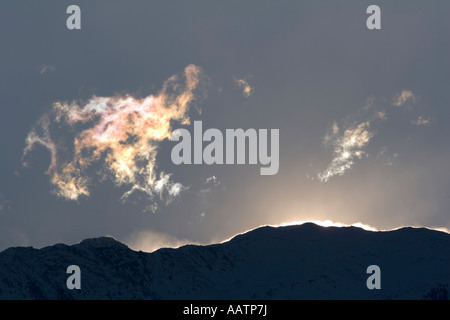Rifrazione della luce tra le nuvole e vento soffiando la neve della montagna creste sopra la Val Venosta, Alto Adige, Italia Foto Stock