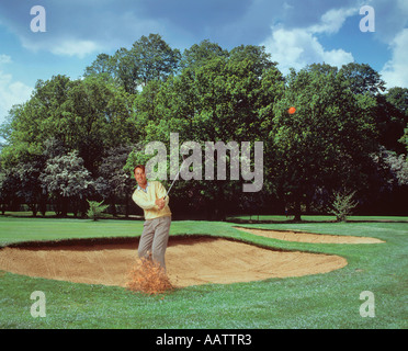 Sport. Attività ricreative. Giovane uomo giocando a golf. Chipping la palla fuori di un bunker di sabbia. Foto Stock