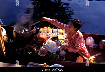 Donna Thai cottura su un sampan nel mercato galleggiante di Damnoen Saduak vicino a bankok in Thailandia Il viaggio internazionale Turismo Foto Stock