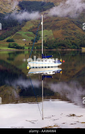 Bianco barca a vela ormeggiata su Loch Leven vicino a Ballachulish Glencoe con luce deriva nuvole dalla cornice montagnosa Foto Stock