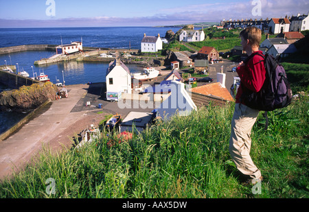 Passeggiate costiere walker guardando verso il basso sulla Scenic village porto di pesca di St Abbs sulla costa Berwickshire Scozia Scotland Foto Stock