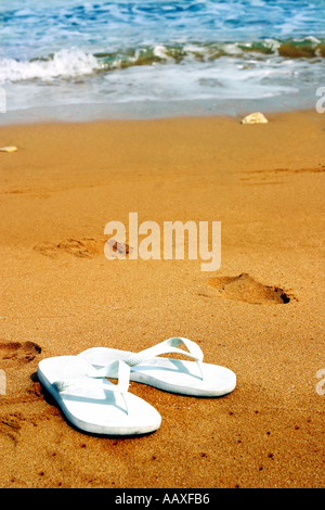 Una coppia di bianco flip flop su una spiaggia Foto Stock