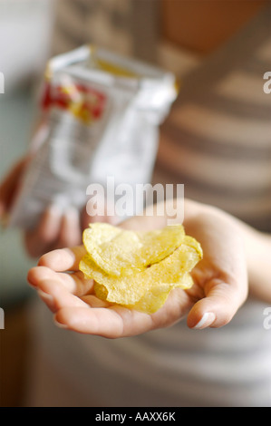 Donna che mantiene le patatine in mani Foto Stock