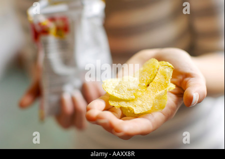 Donna che mantiene le patatine in mani Foto Stock