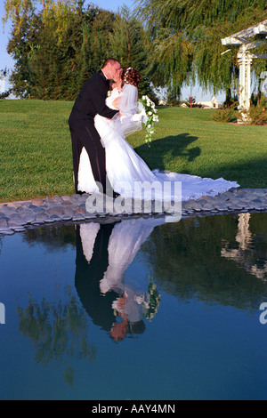 Sposa giovane kissing dopo il matrimonio nell'amore che mostra le spose abito da sposa e sposi verticale tuxedo Foto Stock